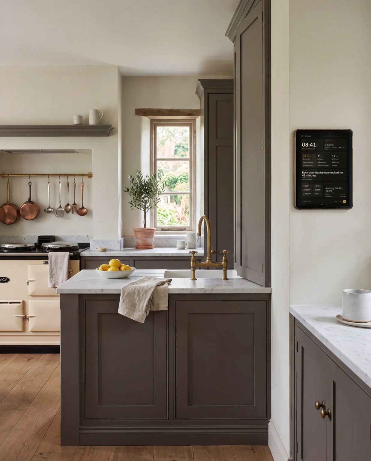 A painted country kitchen in morning light, a portrait screen on the wall beside the larder.